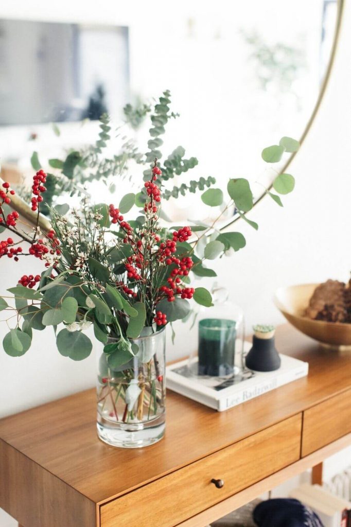 clear vase with greenery and berry twigs